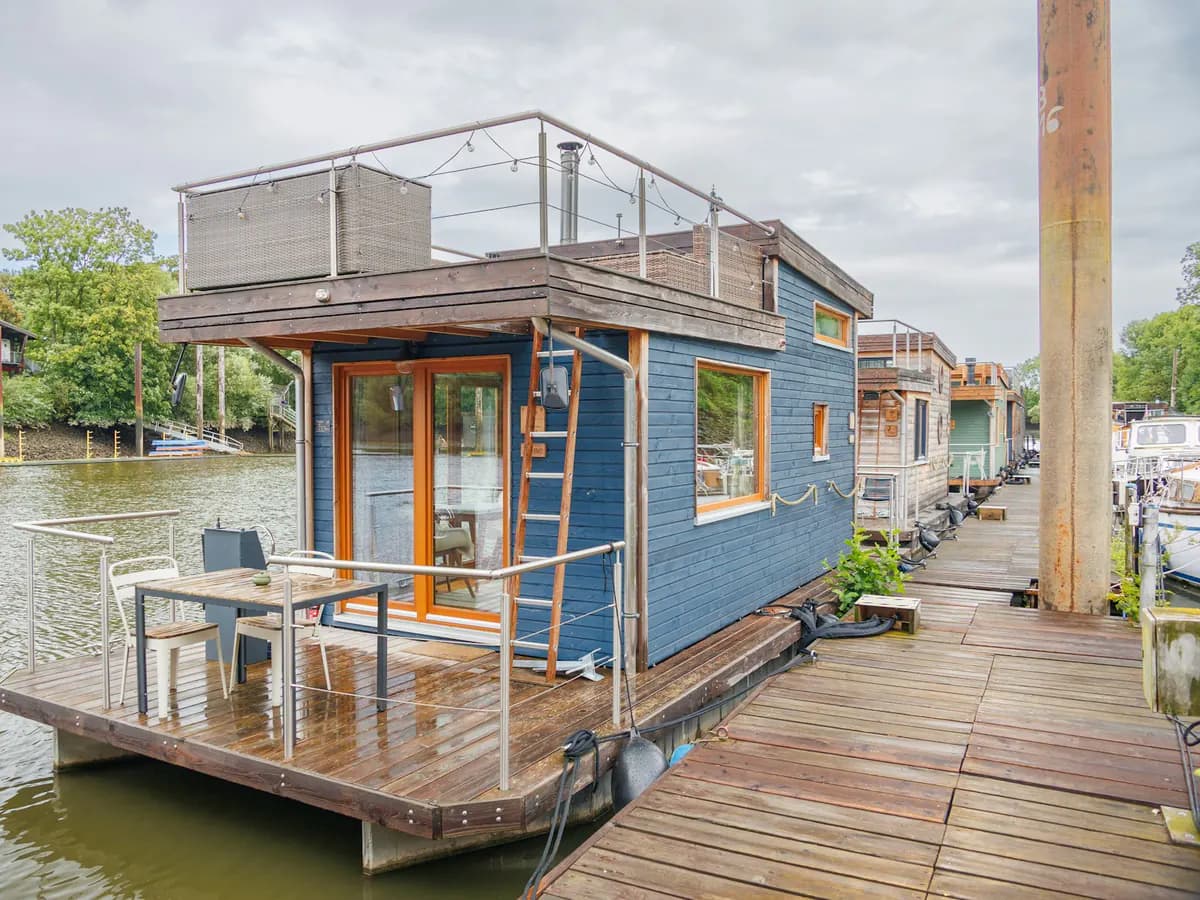 Nowoczesny houseboat z tarasem zacumowany przy drewnianym pomoście